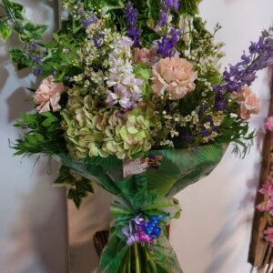 Ramo variado con hortensias, claveles y flores silvestres en tonos pastel, atado con un lazo decorativo, de Floristería Azahar 33.