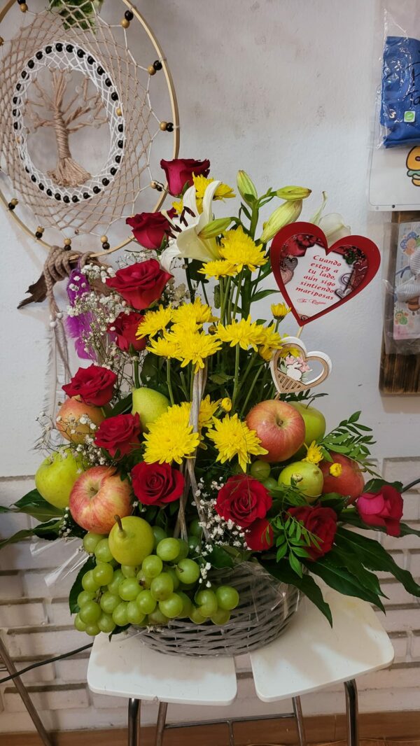 Cesta de frutas variadas y rosas rojas con un globo de 'Feliz Cumpleaños' y decoraciones románticas de Floristería Azahar 33.